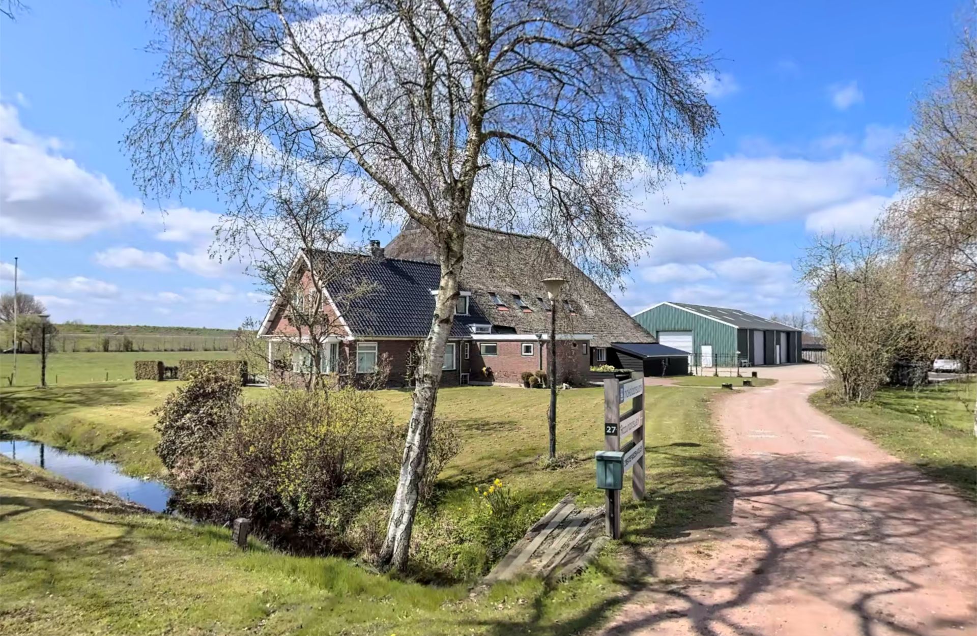 Het kantoor van Hoekstra Bedrijfsadvies aan de Folgeralaan 27 in Drachten: een rietgedekte boerderij met bijgebouw aan een landweg.